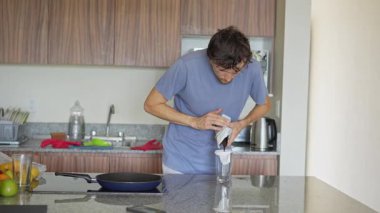 Genç bir adam sütlü filtre kahve hazırlar ve onu içmekten zevk alır. Rahatlatıcı ve tatmin edici bir an kahve yapma, kendine dikkat etme ve rahat bir ev ortamında rahatlama.