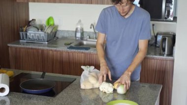 Genç bir adam mutfakta yemek pişiriyor, lezzetli bir ev yemeği hazırlamaya odaklanıyor. Sıcacık bir ortamda ev yapımı, yaratıcılık ve aşçılık keyfi.