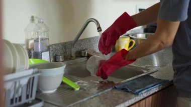 Genç bir adam mutfakta bulaşıkları yıkıyor, temizlik ve düzene odaklanıyor. Basit ve uyumlu bir ev yapımı, ev bakımı ve düzenli bir ev ortamı.