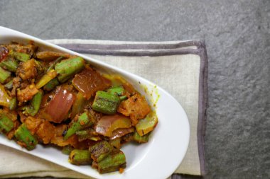 Bir tabak baharatlı ve keskin Bhindi Do Pyaza ya da Gri arkaplanlı Bhindo Masala.