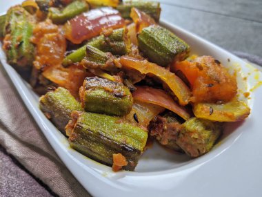 Bir tabak baharatlı ve keskin Bhindi Do Pyaza ya da Gri arkaplanlı Bhindo Masala.