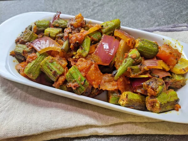 Bir tabak baharatlı ve keskin Bhindi Do Pyaza ya da Gri arkaplanlı Bhindo Masala.