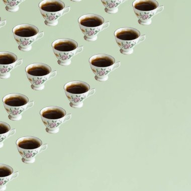Pastel yeşil arka planda eski moda koyu kahve fincanlarından yapılmış bir kalıp. Asgari yaratıcı konsept. Kahve kültürü. Boşluğu kopyala.
