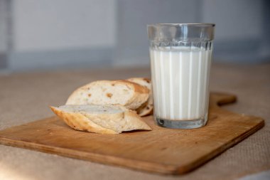 Sütlü cam bardak ve dilimlenmiş ekmek.