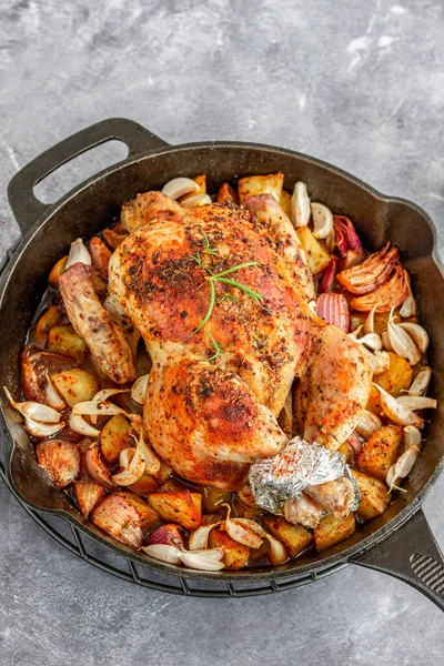 Taze biberiyeyle süslenmiş soğan ve patatesli tam kavrulmuş tavuk, baş aşağı dikey yemek fotoğrafçılığı.