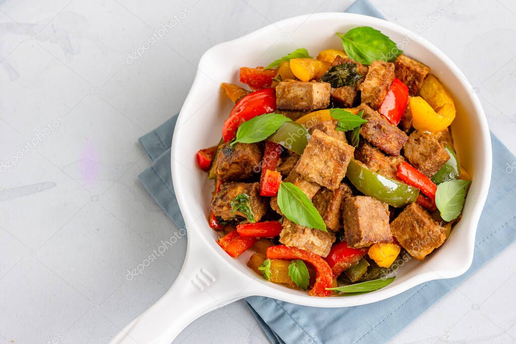 Stir-Fried Tofu and Bell Peppers in a White Skillet Garnished with Thai Basil Leaves,  Directly Above Asian Vegan Food Photography