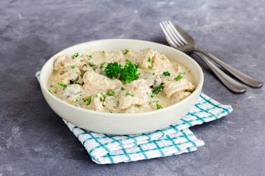 Kremalı tavuk Stroganoff taze maydanozla süslenmiş beyaz bir kasede servis ediliyor. Ekşi krema ve mantar soslu yumuşak tavuk göğsü parçaları, yanında da yumurtalı erişte veya pilav. Klasik konforlu yemek.