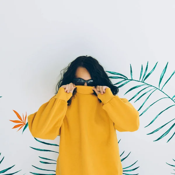 Beautiful girl hides her face in the sweater. Stylish Hoody yellow trendy vibes.