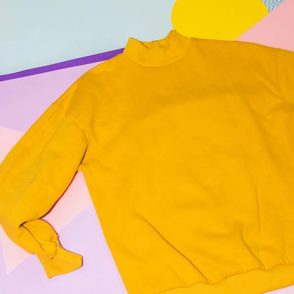 Woman's yellow pullover on memphis style background. Geometry minimal concept. Fall and winter fashion.