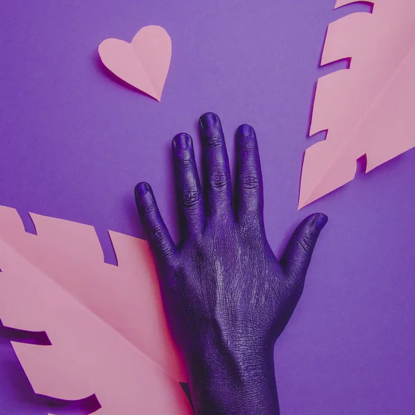 Female hand, showing beauty and skin care symbolism,  minimal fashion background with paper craft pink palm leaves and heart, purple neon colors