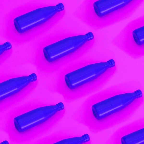 Blue ketchup in plastic bottles on pink background.