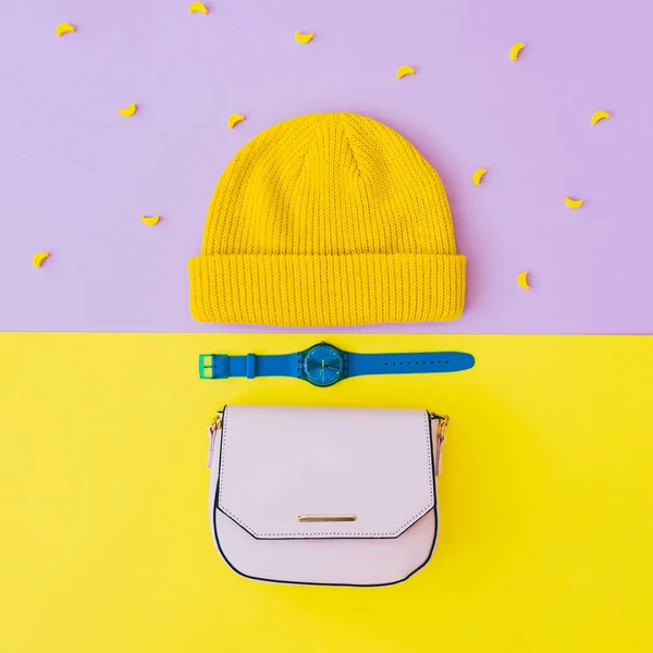 Fashionable flat lay set with yellow beanie hat, blue watches and pink bag