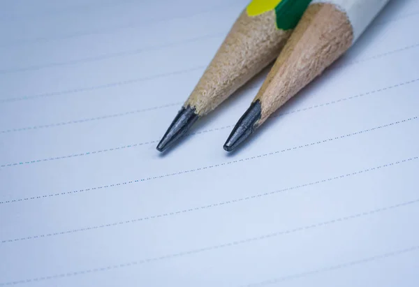 Noktalı kağıda iki sivri uçlu kalem yerleştirilmiş. Eğitim, yazma veya kırtasiye temalı tasarım ve ürün kullanımı için ideal.