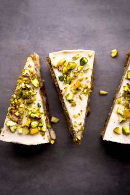 Çiğ vegan fıstıklı havuçlu kek yukarıdan kaju krem katmanlarda beton tablo ile. Karanlık gıda fotoğraf tasarım konsepti. Dikey
