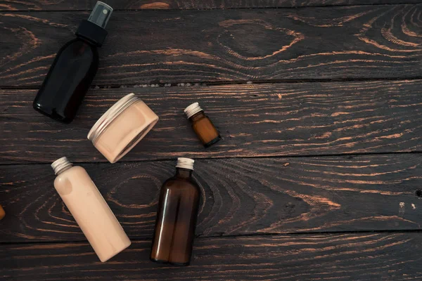 Yukarıdan spa kozmetik ürünlerde koyu kahverengi ahşap masa ile şişe. Güzellik blogger, salon tedavi kavramı. Minimalizm, boşaltmak