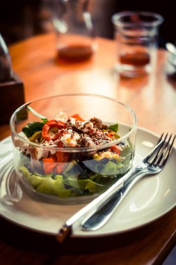 Cam tabak sağlıklı kavrulmuş sebze salatası ahşap bir masa üzerinde. Düşük anahtar gıda fotoğraf, sıcak tonlu filtre