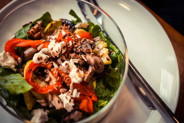 Cam tabak sağlıklı kavrulmuş sebze salatası ahşap bir masa üzerinde. Düşük anahtar gıda fotoğraf, sıcak tonlu filtre