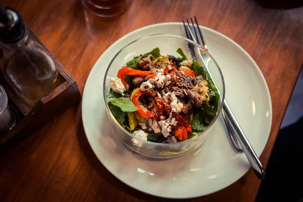 Cam tabak sağlıklı kavrulmuş sebze salatası ahşap bir masa üzerinde. Düşük anahtar gıda fotoğraf, sıcak tonlu filtre