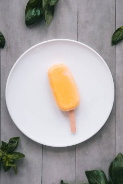 Yukarıdaki beyaz plaka üzerinde ham mango dondurma ve Yeşil fesleğen yaprağı. Gri beton arka plan. Minimalizm gıda Fotoğrafçılık. Boşaltmak