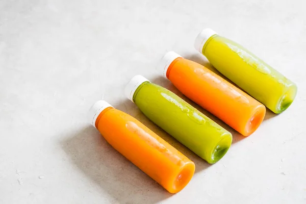 Rad Med Plastflasker Med Kaldpresset Ubearbeidet Frukt Grønnsakjuice Ovenfra Lysegrått stockbilde