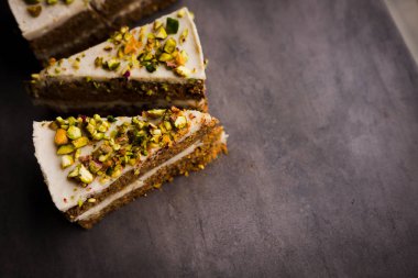 Çiğ vegan fıstıklı havuçlu kek yukarıdan kaju krem katmanlarda beton tablo ile. Karanlık gıda fotoğraf tasarım konsepti.