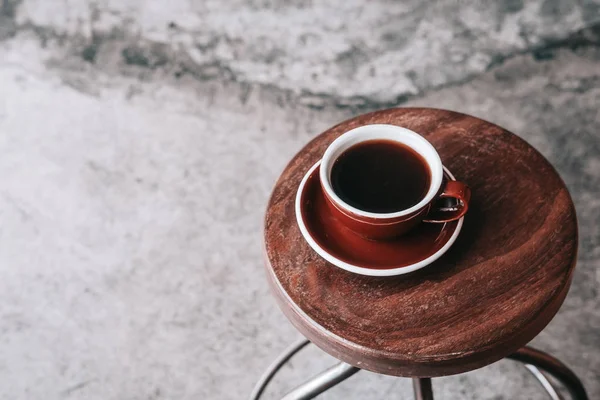 Yukarıdan koyu kahverengi tabakta siyah filtre kahve. Ahşap masa, gri beton zemin, hipster kahve dükkanı. Kopya alanı 