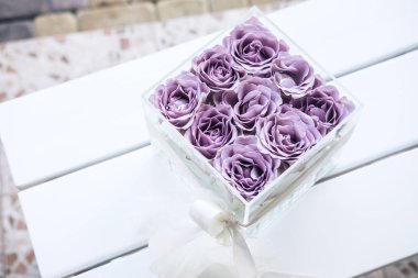 Pastel mor renkli gül akrilik kristal çiçek kutusunu temizleyin. Kare cam hediye kutusu. Yukarıdaki beyaz tahta masada