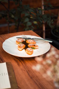Süzme peynir krep beyaz tabakta. Ahşap masa. Gıda fotoğrafçılığı kavramı. Sıcak renkler filtre