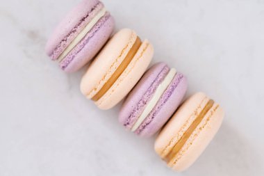 Sarı ve Mor pastel renkli Fransız macarons yukarıdan beyaz mermer masada