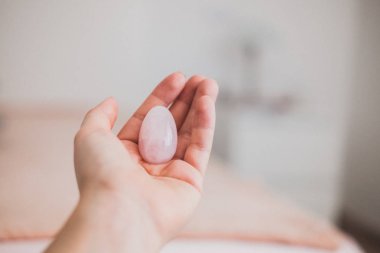 Elinde bir vajinal yumurta tutan bir kadın. Gül kuvars kristal yumurtası. Kopyalama alanı