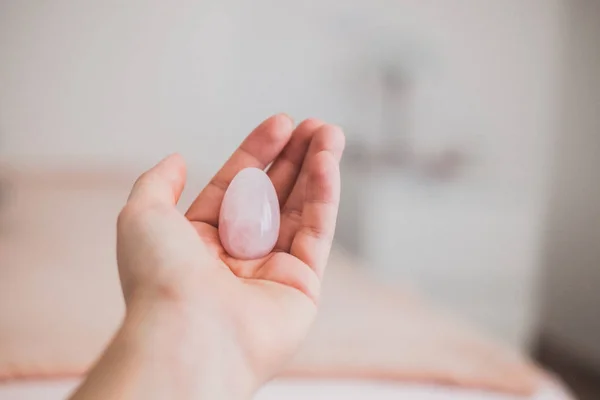 Elinde bir vajinal yumurta tutan bir kadın. Gül kuvars kristal yumurtası. Kopyalama alanı