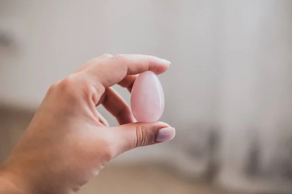 Elinde bir vajinal yumurta tutan bir kadın. Gül kuvars kristal yumurtası. Kopyalama alanı