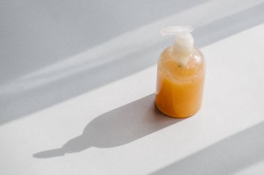 Yukarıdan organik kozmetik ürün ile açık bir plastik şişe. Doğrudan güneş ışığı ve gölgeler. Güzellik bloglama minimalizm kavramı