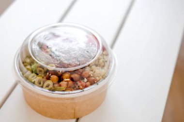 Salata tek kullanımlık craft kağıt kase beyaz zemin üzerine götürün. Minimalizm gıda fotoğrafçılığı kavramı. Mockup, boşaltmak