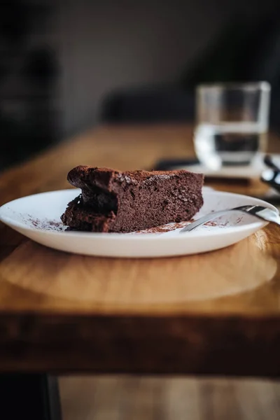 One slice of vegan chocolate brownie cake on wooden table. Sugar free, wheat free, dairy free, flourless dessert. Dark mood food photo. Healthy eating, lifestyle concept. Copy space