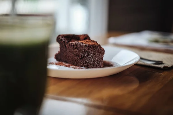 One slice of vegan chocolate brownie cake on wooden table. Sugar free, wheat free, dairy free, flourless dessert. Dark mood food photo. Healthy eating, lifestyle concept. Copy space