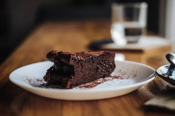 One slice of vegan chocolate brownie cake on wooden table. Sugar free, wheat free, dairy free, flourless dessert. Dark mood food photo. Healthy eating, lifestyle concept. Copy space