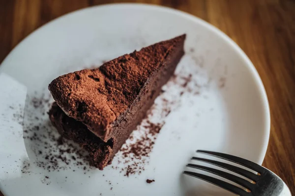 One slice of vegan chocolate brownie cake on wooden table. Sugar free, wheat free, dairy free, flourless dessert. Dark mood food photo. Healthy eating, lifestyle concept. Copy space