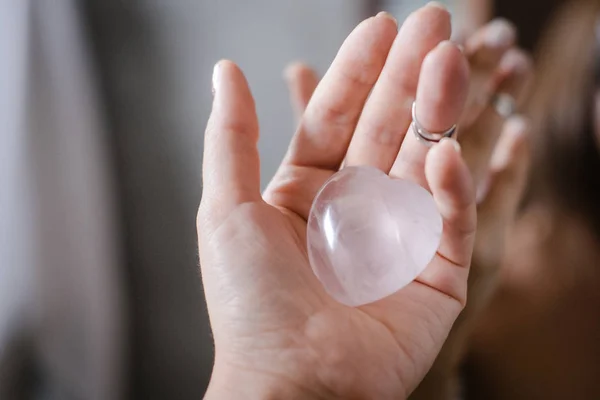 Frau hält Rosenquarz-Herzkristall in der Hand — Stockfoto