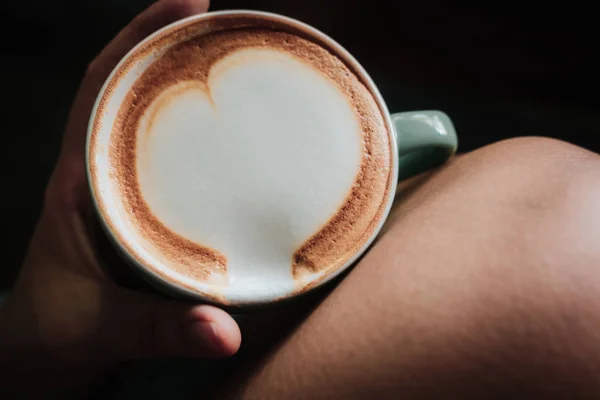 Donna mano che tiene il caffè con arte del latte del cuore — Foto Stock