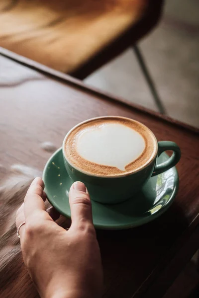 Woman hand holding coffee with heart latte art — Stock Photo, Image