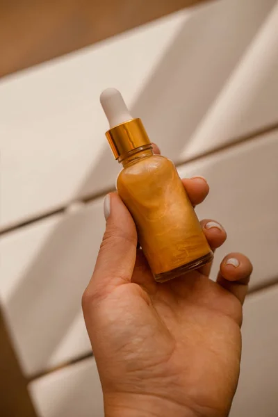 Wanita memegang di tangan satu botol kosmetik gelas — Stok Foto