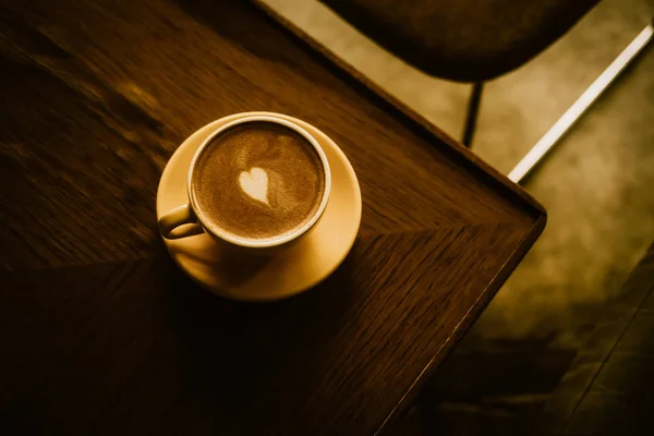 Kawa cappuccino z sercem w żółtym filiżance — Zdjęcie stockowe