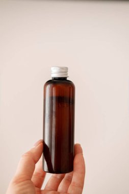 Elinde cam kozmetik şişesi tutan kadın.