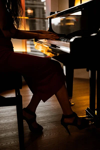 Elegant woman playing on piano, dark photo
