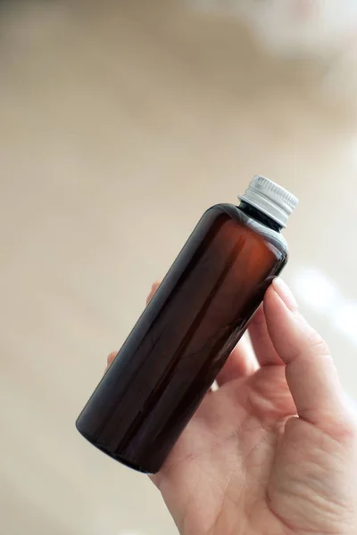 Mujer sosteniendo vidrio cosmético botella marrón Fotos de stock