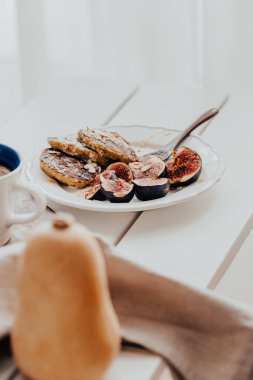 Beyaz ahşap masada incirli balkabağı krepleri.