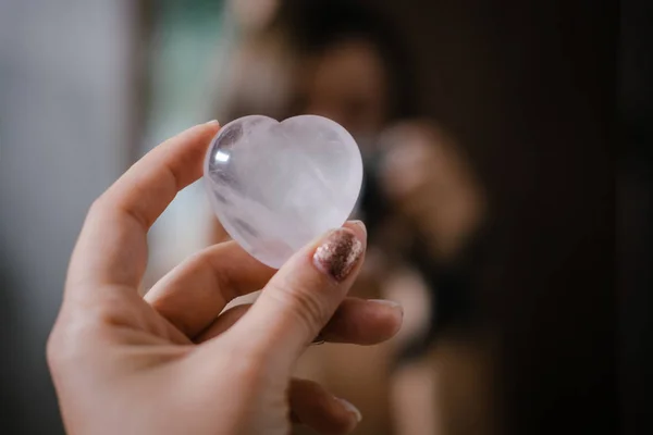 Frau hält Rosenquarz-Herzkristall in der Hand — Stockfoto