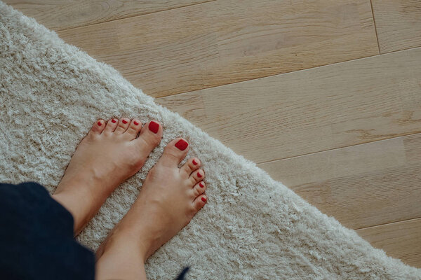 Woman feet on carpet and wooden laminate floor