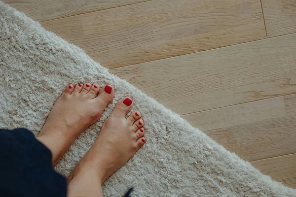 Woman feet on carpet and wooden laminate floor Royalty Free Stock Images